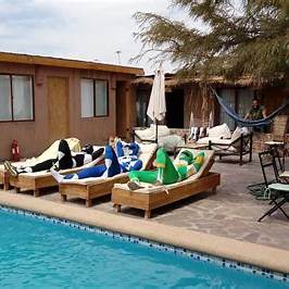 Patio interior de hostal en San Pedro de Atacama con sillas, mesones y estilo rústico, perfecto para mochileros y presupuesto ajustado.